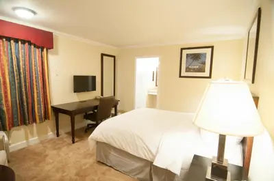a bedroom with a bed and a desk with a computer at Bokai Garden Hotel in Rosemead