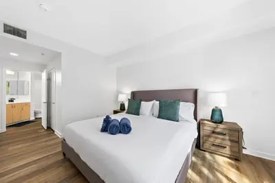 a bedroom with a large white bed with two blue bags on it at The Turquoise Lounge - Chic 2BR Beach view Pool, Sauna in Los Angeles