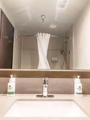 a bathroom sink with two soap dispensers and a mirror at GreenTree Inn & Suites Los Angeles - Alhambra - Pasadena in Alhambra