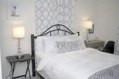 a bedroom with a white bed with two lamps and a chair at LBC Cozy Suite -Downtown! Beach! in Long Beach