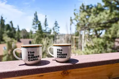 two coffee cups sitting on top of a balcony at Cozy Cabin near Resorts and The Village +Mtn views in Big Bear City
