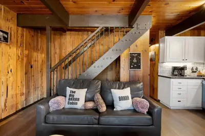 a leather couch in a living room with a staircase at Cozy Cabin near Resorts and The Village +Mtn views in Big Bear City
