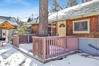 a house with a wooden fence in the snow at Sunset Cottage Lakeside Couple's Cabin by Big Bear Vacations in Big Bear Lake