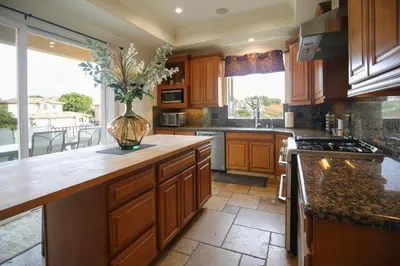 a kitchen with wooden cabinets and a vase with flowers at 5 BR/5 BA Getaway with a View in Thousand Oaks