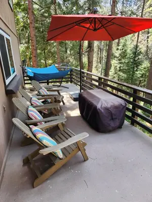 two deck chairs and an umbrella on a porch at “The Grey Haven” – Secluded home in the woods in Lake Arrowhead