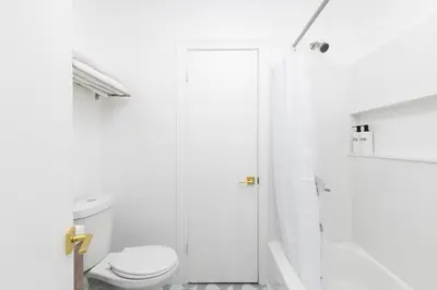 a white bathroom with a toilet and a shower at Aliza Hotel in Los Angeles