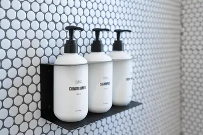 a group of four white bottles on a shelf in a bathroom at Aliza Hotel in Los Angeles