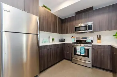 a kitchen with wooden cabinets and a stainless steel refrigerator at Cozy 3bed Condo with balcony and a rooftop pool in Los Angeles