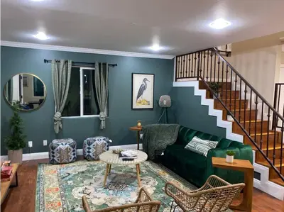 a living room with a green couch and a staircase at Big & Cozy Duplex Home in Los Angeles