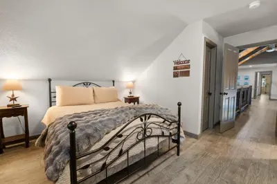 a bedroom with a bed and a hallway at Evergreen -LUXURY CABIN WITH A HOT TUB, GAME ROOM & 3 EN-SUITE BEDROOMS! in Big Bear Lake