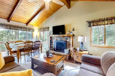 a living room with a fireplace and a table at Idyllic Cabin in the Woods Cozy Crestline Retreat in Arrowhead Highlands