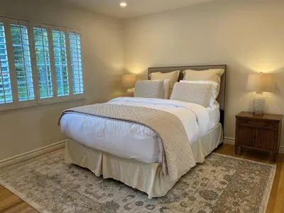 a bedroom with a bed with white sheets and pillows at Guest house with private entry and large pool in Los Angeles