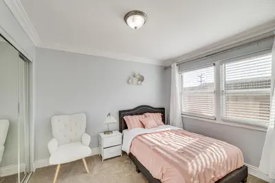 a bedroom with a bed and a white chair at Furnished Patio! South Central Home 14 Mi to DTLA in Compton