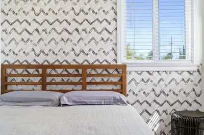a bedroom with a bed and a wall with a window at Newly Remodeled Home in the Heart of Orange County in Midway City