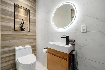 a bathroom with a toilet and a sink and a mirror at Newly Remodeled Home in the Heart of Orange County in Midway City