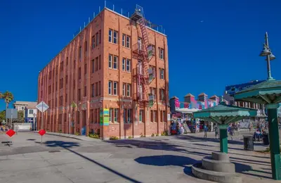 a large red brick building in front of a street at Venice Breeze Suites in Los Angeles