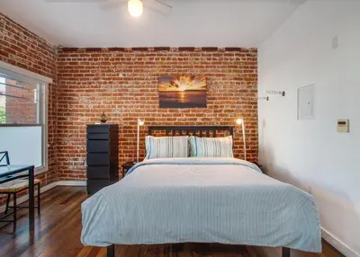 a bedroom with a brick wall and a bed at Venice Breeze Suites in Los Angeles