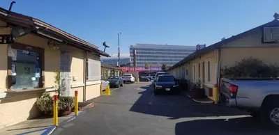a street with cars parked on the side of buildings at Hollywood Park Motel in Inglewood
