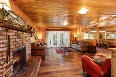 a living room with a brick fireplace in a house at Arrowhead Pine Rose Cabins in Twin Peaks