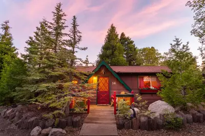 a house with a red door in the woods at Arrowhead Pine Rose Cabins in Twin Peaks