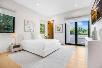 a white bedroom with a white bed and large windows at Levitt Lane in Los Angeles