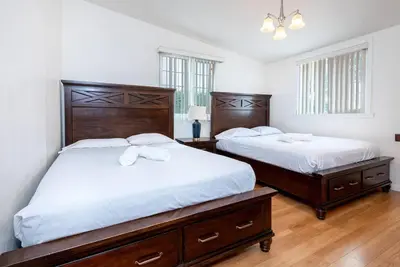 two beds in a bedroom with white walls and wood floors at Central LA Bliss: 5 BR Home, BBQ, Perfect Location in Los Angeles