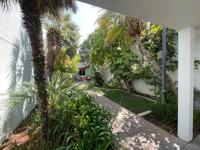 a garden with palm trees and a walkway at Hotel Pacific Garden in Gardena