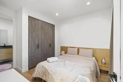 a bedroom with a large bed and a wooden cabinet at Scandinavian 2BR, 2Bath Townhome, Pet & Kid Friendly, Free Parking, 10min to Venice Beach! in Los Angeles