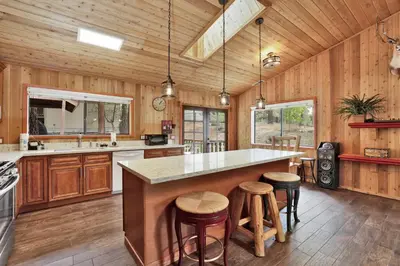 a kitchen with wooden walls and a large island with bar stools at Pines and needles #1454 in Big Bear Lake