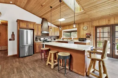 a kitchen with wooden cabinets and a large island with bar stools at Pines and needles #1454 in Big Bear Lake
