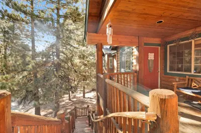 a porch of a wooden cabin with a red door at River rock lodge #1953 in Big Bear Lake