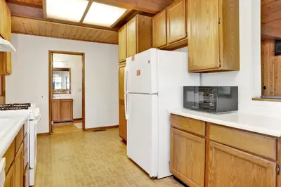a kitchen with a white refrigerator and wooden cabinets at Breezy one #112 in Big Bear Lake