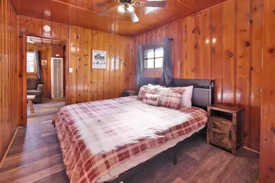 a bedroom with a bed with wooden walls and a ceiling at Little pines #102 in Big Bear Lake