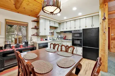 a kitchen with a table and chairs and a black refrigerator at Timber pines chalet #2417 in Big Bear Lake