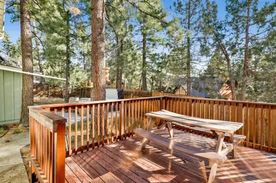 a wooden deck with a picnic table and a bench at Mountain fun #1729 in Big Bear Lake