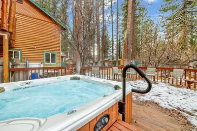 a jacuzzi tub on the deck of a log cabin at Flitterbick lodge #2246 in Fawnskin