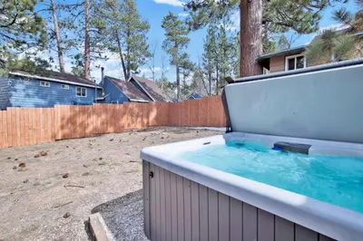 a hot tub in a backyard with a fence at Storyville #2294 in Big Bear Lake