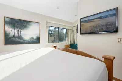 a bedroom with a white bed and two windows at Forest shores lake view condo #2250 in Big Bear Lake