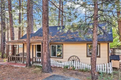 a small house with a white fence in the woods at Pines 23 #1438 in Big Bear Lake