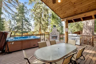 a patio with a table and a hot tub on a deck at Moose manor #2012 in Big Bear Lake