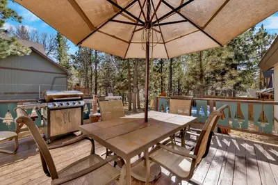 a wooden table and chairs with an umbrella on a deck at Moose creek chalet #1237 in Big Bear Lake