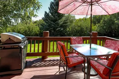 a grill and a table and chairs on a deck with an umbrella at Cienega getaway #1952 in Big Bear Lake