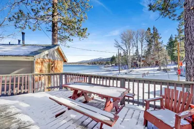 a picnic table and chairs on a deck with a view of a lake at Shore acres lodge #450 in Big Bear Lake