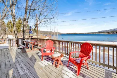 two red chairs and a table on a deck with a lake at Sunrise #108 in Big Bear Lake