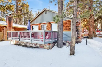 a log cabin with a deck in the snow at Lakeside #109 in Big Bear Lake