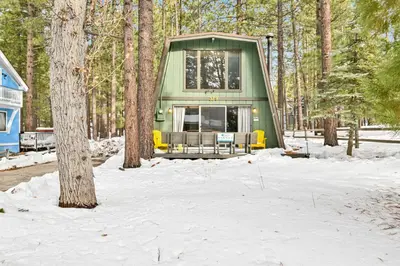 a green cabin in the woods in the snow at QUAIL'S CALL #2415 in Big Bear Lake