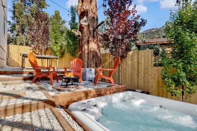 a hot tub in a backyard with chairs and a table at Chimney Peak Chalet#2048 in Big Bear City