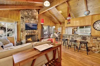 a living room with a fireplace and a stone wall at Marin getaway #2013 in Big Bear Lake