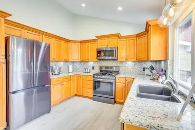 a kitchen with wooden cabinets and a stainless steel refrigerator at Idyllic Tustin Home with Private Patio and Grill in Tustin