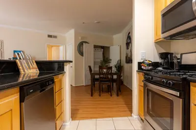 a kitchen with black counter tops and a dining room at Urban Haven at Orsini in Los Angeles